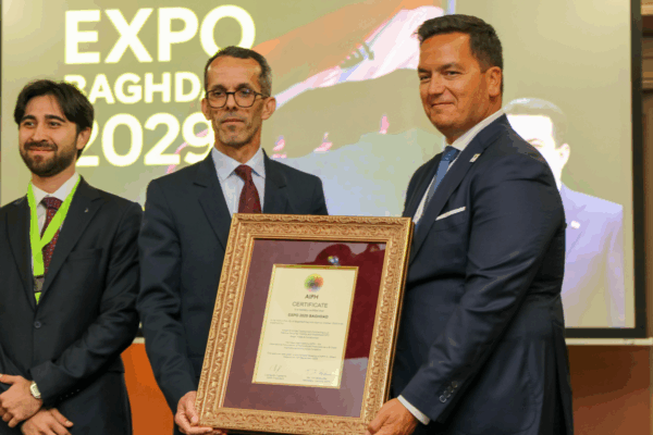 Presentation of the AIPH certificate of approval for Expo 2029 Baghdad. The AIPH President (right) holds the framed certificate with an Iraqi diplomat (centre), while the Expo 2029 Garden CEO (left) stands alongside. The Expo 2029 Baghdad logo is displayed in the background.