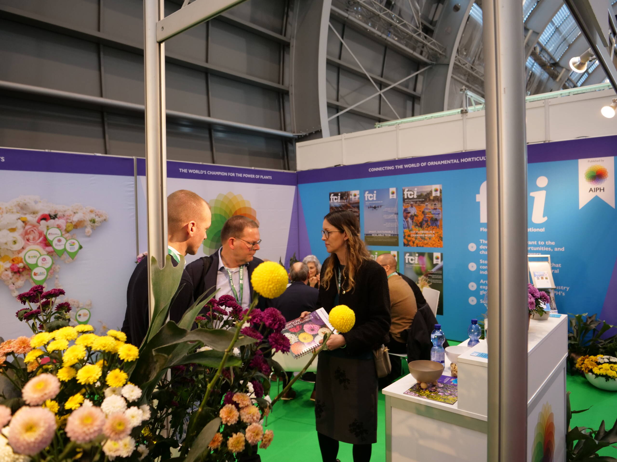 Industry discussions at the AIPH stand during IPM Essen, with publications and donated flowers supporting informal meetings.