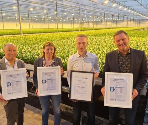 Jin Hoeksema, Simone Rodewijk, John Vreugdenhil and Henri Potze holding footprint validation certificates inside KP Holland greenhouse.
