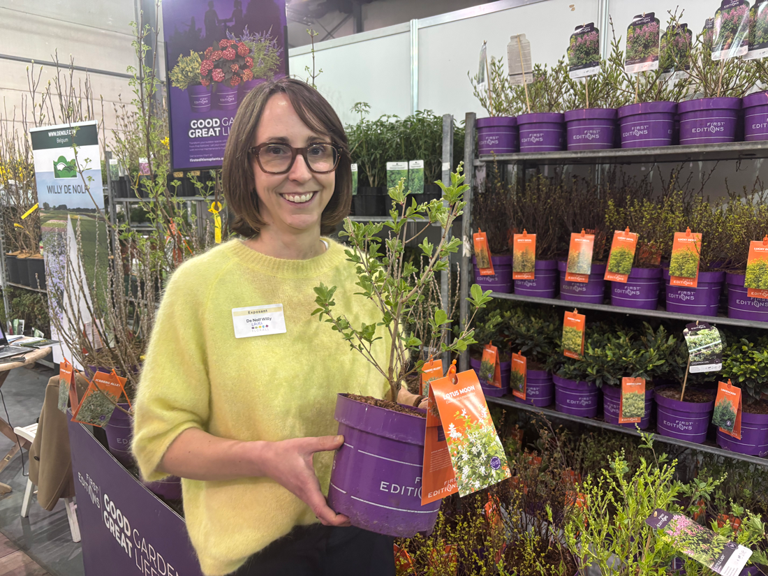 Laura De Nolf holding a potted Exochorda × macrantha ‘Lotus Moon’ plant at the Willy De Nolf nursery stand at Florall.
