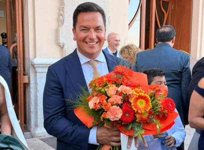 Leonardo Capitanio smiles while holding flowers and his Cavaliere certificate outside the ceremony venue.