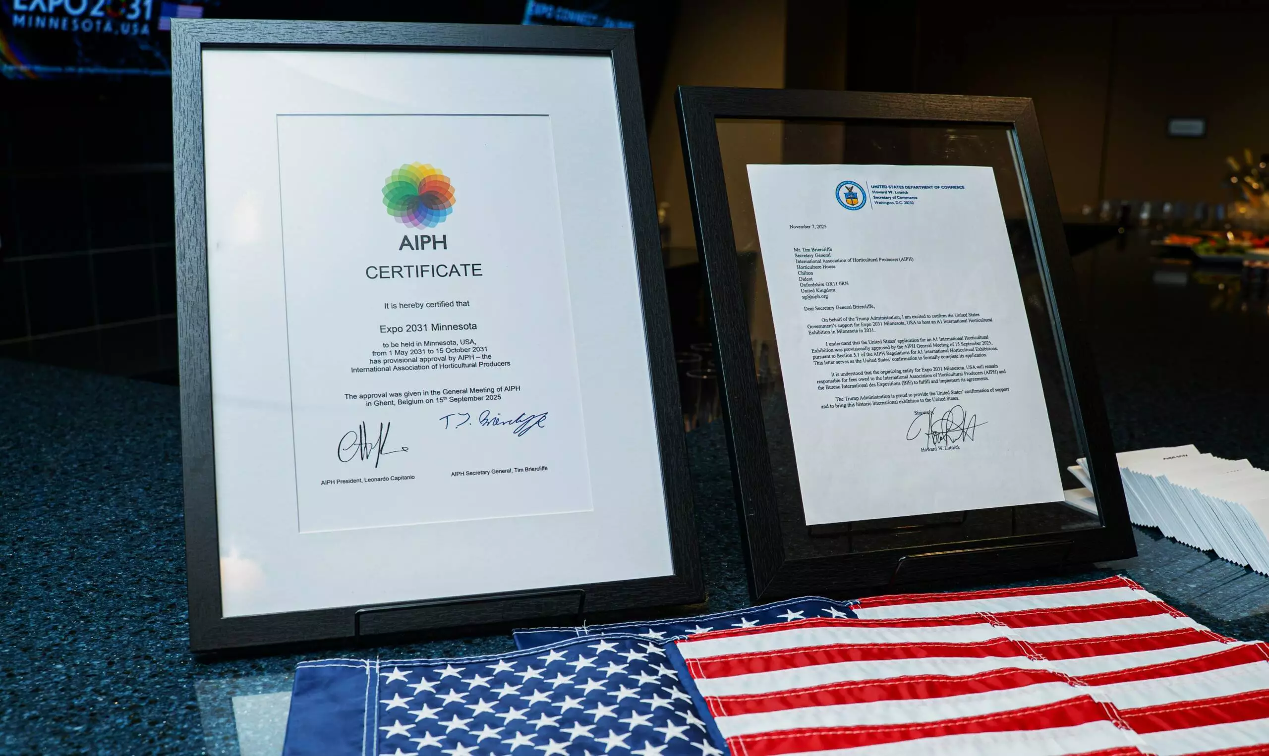 Framed AIPH provisional approval certificate and framed U.S. federal letter of support displayed on a counter with an American flag.